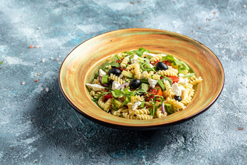 Greek Pasta Salad with tomato, avocado, black olives, red onions and cheese feta. Long banner format, top view