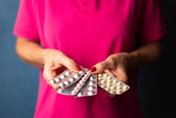 Woman holds several pill packs in her hands in a fan shape on a blue background - Medical supplies