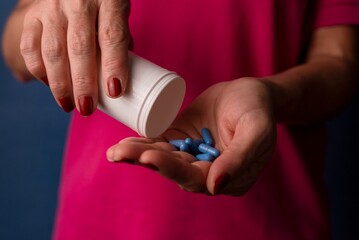 Woman pouring blue pills from the container into his hand - Medical supplies concept