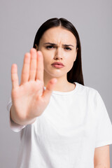 Serious concentrated young woman wearing white t-shirt looking at camera saying stop to domestic...