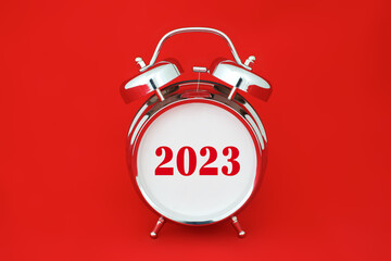 2023 number on empty face of chrome retro alarm clock isolated on red background