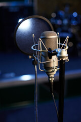 Microphone with a pop shield closeup on the background of a professional recording studio....