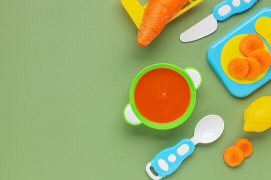 Carrot puree in a bowl and toy plastic utensils. Baby food concept. Top View. Copy space
