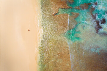 Drone View of a man having a beautiful beach walk next to a coral reef. Thailand