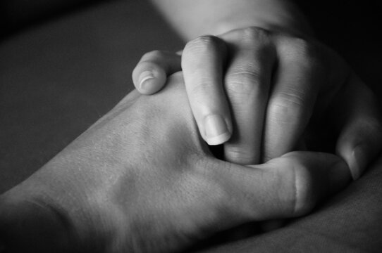 Two hands of a man and a woman holding each other in black and white
