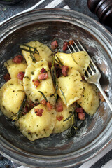 Homemade ravioli with potato and ricotts cheese served with crispy bacon. Top view with copy space. 