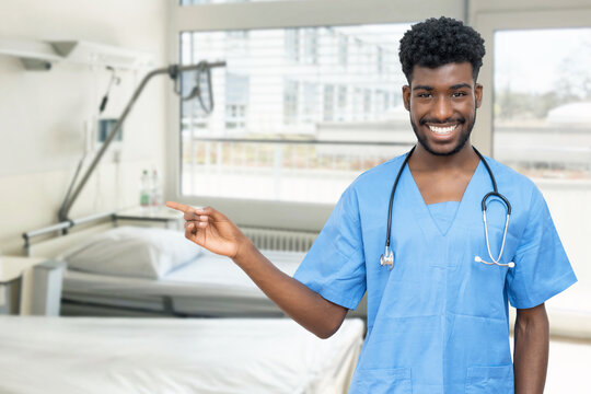Young african american doctor or male nurse pointing sideways at hospital room