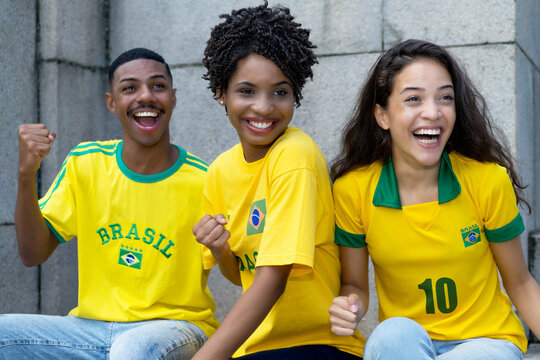 Group of cheering football fans from Brazil with yellow soccer jersey