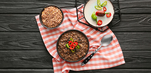 Bowl of tasty lentils soup and chili pepper on dark wooden table