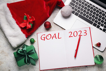 Notebook with blank to-do list for year 2023, gift, Santa hat and laptop on light background