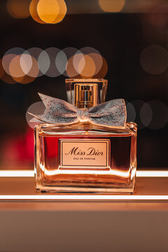 Glass bottle of Miss Dior luxury perfume on a stand with golden bokeh light. It was founded in 1946 by French fashion designer Christian Dior.