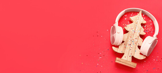 Headphones and wooden Christmas tree on red background with space for text