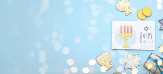 Different symbols of Hanukkah and greeting card on light blue background with space for text