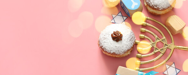 Fototapeta na wymiar Menorah, dreidels and donuts for Hanukkah celebration on pink background with space for text
