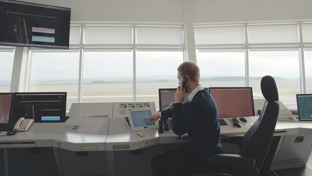 Air Traffic Controller Talk on phone in Airport Tower looking away using binoculars. Realtime.