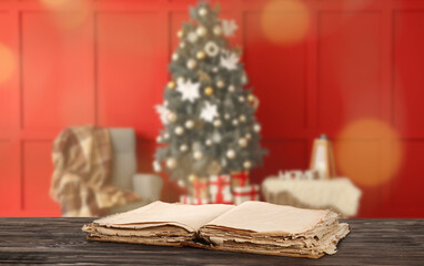 Open old book on table in room with decorated Christmas tree