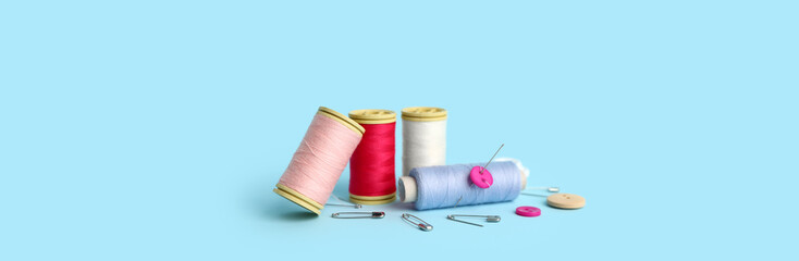 Set of sewing supplies with thread spools on light blue background