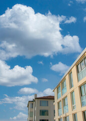 Vertical White puffy clouds Two low rise buildings with glass panels at La Jolla, California
