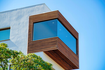Home cubby with wooden facade on white stucco exterior of house or home or building in late afternoon sun and front yard trees