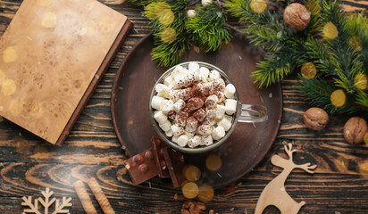 Cup of hot chocolate with marshmallows and book on wooden background