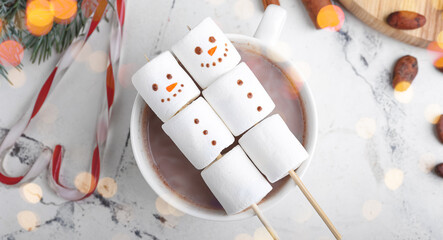 Snowmen made of soft marshmallows and cup of hot chocolate on light background, top view