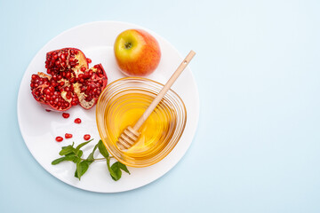 Jewish New Year Rosh Hashanah Traditional background with apple, ripe pomegranate and honey on a plate