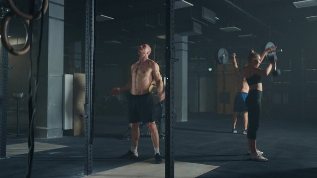 group of professional bodybuilders training in gym, men and women lifting weights, tensing muscles