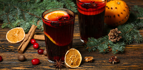 Glasses of aromatic mulled wine on wooden background