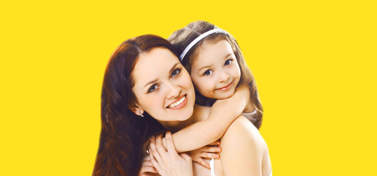 Portrait of happy smiling mother with daughter child on yellow background