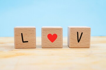 the letters of love represented in three wooden blocks on a blue background with copy space