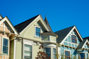 Row of historic houses in San Francisco California with front yard trees and clear blue sky background with beige and blue color