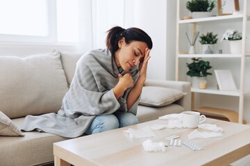 A woman with a cold pills is treated at home chooses which medicines to take and self-medicates, checks the expiration date while sitting at home on the couch, temperature, allergies and covid-19