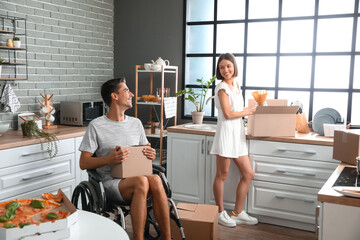 Young woman and her husband in wheelchair in kitchen on moving day