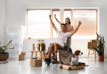 Young woman with her husband in wheelchair and dog in their new house on moving day