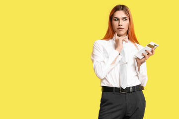 Thoughtful transgender secretary with calculator on yellow background