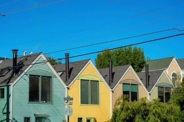 Row of colorful house or home facades with blue and beige and yellow with back yard trees and visible windows near powerlines