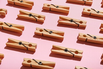 Many wooden clothespins on pink background