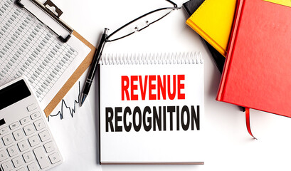 REVENUE RECOGNITION text on notebook with clipboard and calculator on white background