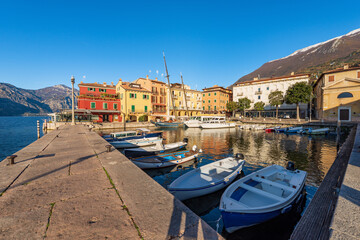 Fototapeta na wymiar Malcesine village. Port with small boats and ferries moored and colorful houses. Famous tourist resort on the coast of Lake Garda (Lago di Garda). Verona province, Veneto, Italy, southern Europe.