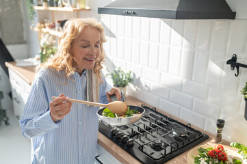Blonde woman cooking and looking enjoyed
