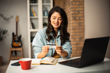 Pregnant woman shopping online at home. Happy woman with laptop and credit card..