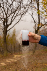 A hand with a glass of magic floating autumn mulled wine drink