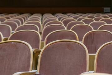 Close up of red wooden cinema seats, covered with red fabric, in old historical cinema.