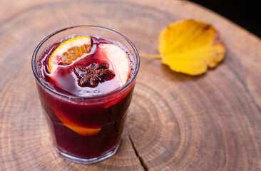 Hot and fragrant mulled wine in a glass on a wooden table. Seasonal warm drinks. Close-up....