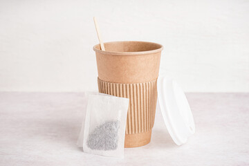 Paper cup and tea bag on light background