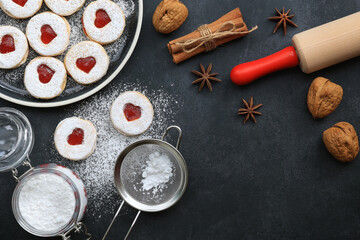 A plate of cookies, spices,powdered sugar,rolling pin, colander on dark background