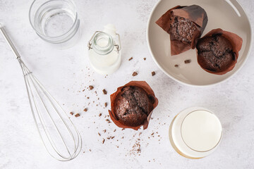 Sweet chocolate muffins and milk on light background