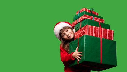 A little girl in a Santa hat is holding a lot of gift boxes. New Year's gifts for Christmas. 2023. Isolated on a green background