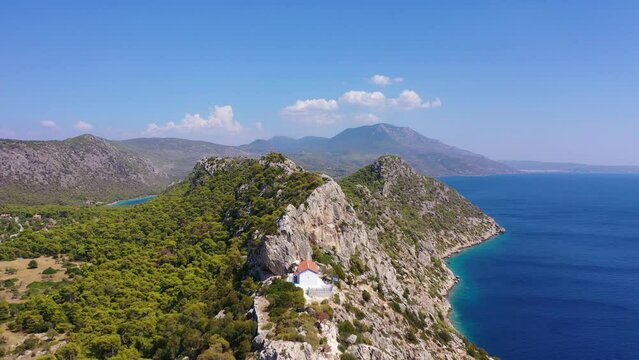 Aerial drone video of famous archaeological site of Heraion in Cape Melagavi featuring a small beach next to iconic lake Vouliagmeni and lighthouse, Corinthian bay, Perachora, Loutraki, Greece