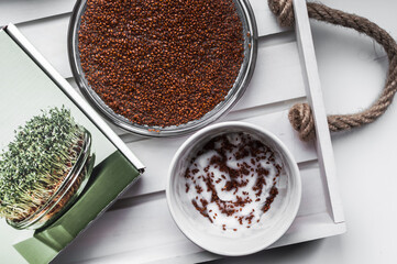 Sown seeds of watercress in a glass bowl and ceramic container closeup.